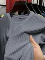 Nahaufnahme der grauen Eisseiden-Netzstruktur eines Herren-T-Shirts mit Rundhals. - Hellgrau