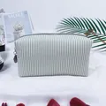 Detailed macro shot of a green and white striped seersucker makeup bag with a zipper. - Army Green
