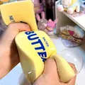 Detail shot of hands squeezing a yellow salted butter-shaped stress relief toy - 13cm Butter Stick