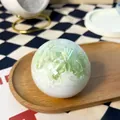 Runder grün-weißer Stressabbau-Quetschball Spielzeug auf einem Holztablett Hintergrund - Minz-Crushed Ice Stil / 1 Stück