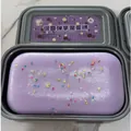 Lila Taro-Kuchen Squishy-Spielzeug mit bunten Streuseln in einer grauen Plastikbox - Taro-Kuchen Quetschen
