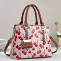 Détails d'un sac à main rose à imprimé cerises avec poignées marron et pendentif - Rose