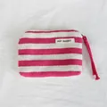 Close-up detail of a pink and white striped canvas coin purse with wrist strap and label - Rose Red Striped