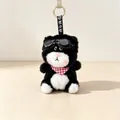 Close-up of a cute plush cat keychain with black goggles and a red gingham scarf. - Black Cat