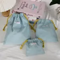 Three light blue Oxford fabric drawstring bags in various sizes with yellow ropes - Three-Piece Set / Blue