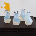 Macro view of four translucent opalite rabbit crystal carvings on a dark wood base. - Opalite