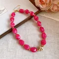 Vista dettagliata della collana vintage con perle in acrilico marmorizzato rosa e oro. - Rosa Rosso