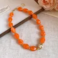 Dettaglio ravvicinato di perle in acrilico arancio marmorizzato su collana retrò - Arancione