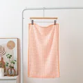 Soft orange and white checkered cotton tea towel hanging on a minimalist rack - Orange