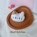 Detailweergave van een zachte witte pluche kattenbroche met blauwe ogen en gouden oortje - DIY-stijl (Achterkant open) / Witte kat