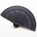 Close-up detail of an elegant black hollow carved wooden folding fan for wedding dancing - 20cm / Black