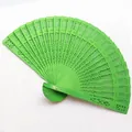 Detailed view of a bright green hollowed-out wooden folding fan with intricate carvings - 20cm / Light Green