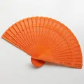 Detailed macro view of intricate hollow-out floral carvings on a bright orange wooden fan - 20cm / Orange