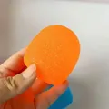 Primo piano dettagliato di una palla antistress arancione strutturata tenuta in una mano - Stile Caramella Media (Maltosio) / Arancione