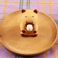 Gros plan d'un adorable jouet anti-stress Capybara posé sur un plateau en bois rond - Modèle Capybara