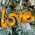 Detailopname van warmgele LED 'LOVE' decoratieve verlichting op besneeuwde boom - LOVE Lamp / Goud