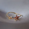 Anello regolabile in oro con stella marina in zircone rosso e motivo conchiglia - Aperto Regolabile / Tema Oceano Zirconia Multicolore (JZ029)