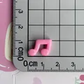 Close-up detail view of a mini pink music note resin charm shown on a centimeter scale ruler - Rose Red
