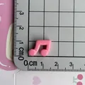 Close-up detail view of a mini pink musical note resin charm on a measurement grid - Watermelon red