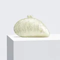 Detailed macro view of pearlescent shell-shaped acrylic clutch with elegant pearl clasp - Milky White