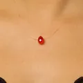 Close-up of a red faceted crystal teardrop pendant on an invisible fishing line necklace. - Red