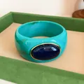 Detailed view of a retro turquoise acrylic wide bangle with a dark blue oval stone. - Vintage Wide Style (HB6269) / Cyan & Dark Blue