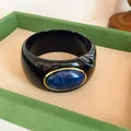 Detailed close-up of a retro black acrylic wide bangle with a blue oval resin stone - Vintage Wide Style (HB6269) / Black and Dark Blue