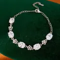 Primo piano di un elegante bracciale in zircone e fiori su sfondo di velluto verde - Stile Fiore Zirconia Ovale Bianco / Argento