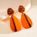 Close-up detail of amber resin teardrop earrings featuring artistic black ink marbling effect - Orange