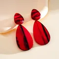 Close-up of red and black marbled resin drop earrings with geometric waterdrop design. - Stud Pin Style / Red