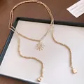 Close-up of golden sun pendant with spiral design on a geometric bead necklace - Sun Pendant Long Necklace (HN12962) / Gold