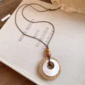 Vue détaillée d'un collier pendentif en raphia et résine avec perles de bois sur lin. - Style avec Accent en Résine Blanche / Collier-Marron-Blanc