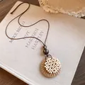 Détail du collier à pendentif circulaire en raphia sur couverture de livre épurée - Style Embelli de Perles / Collier-Café-Perlé