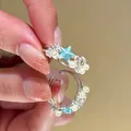 Detailweergave van een zilveren ring met een blauwe emaille ster en witte parels - Ster en Parel Stijl (2#) / Zilver Blauw