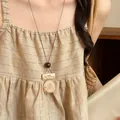 Detail of vintage New Chinese style necklace with marble textured pendant on linen dress. - Coffee & Cream White