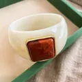 Close-up of wide acrylic bangle featuring a square orange marbled stone setting - Ivory Base Red Square / Ivory White-Red