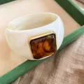 Dettaglio di un bracciale in acrilico con elemento in resina ambra e bordo dorato. - Bianco Avorio-Caffè