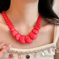 Close-up of a vibrant red stone necklace with marbled texture on a model - Red