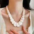 Detail view of a white marbled stone necklace on model for island vacation style - White