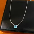 Primer plano de collar de circonita azul claro sobre elegante joyero de cuero negro - Colgante Cuadrado