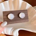 Close-up of retro silver earrings with milky white agate stones on wood - White
