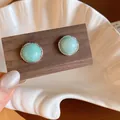 Close-up of vintage light green agate stone stud earrings with silver textured bezel - Blue