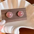 Detail of retro pink agate stud earrings with textured silver frame on wood card. - Pink