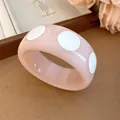 Detail view of a pink resin bangle featuring a stylish white polka dot pattern. - Style 3