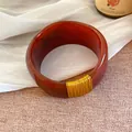 Gros plan détaillé sur un bracelet large en résine avec motif marbré rouge et fil doré - Or-Brun