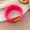 Vue détaillée d'un bracelet en résine rose marbrée avec un enroulement de fil doré. - Or-Rose Rouge