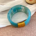 Détail d'un large bracelet en résine marbrée bleue avec une décoration en fil doré - Or-Cyan