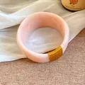 Vue détaillée d'un bracelet en résine marbrée rose avec enroulement de fil d'or. - Or-Pêche