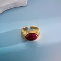 Primer plano de anillo abierto bañado en oro 18k con textura plisada y piedra granate - Estilo de Gema Roja / Dorado