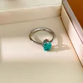 Gros plan d'une bague en argent avec un zircon vert émeraude dans un écrin à bijoux - Couleur Paraïba